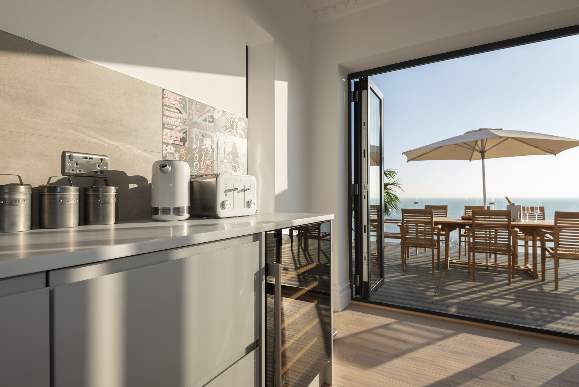 Open-plan kitchen opening onto sun deck and sea
