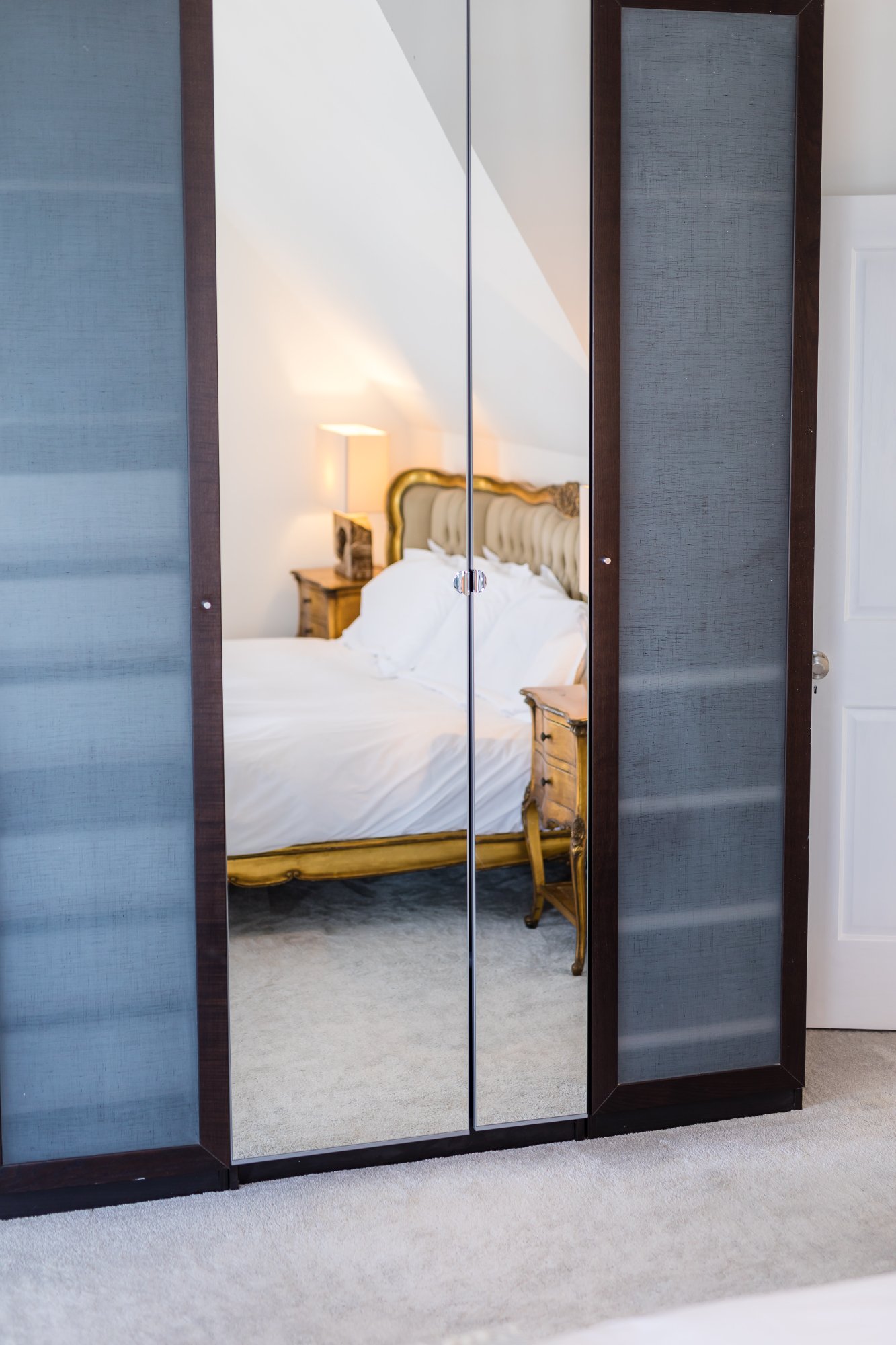 Mirrored wardrobe reflecting gold bed
